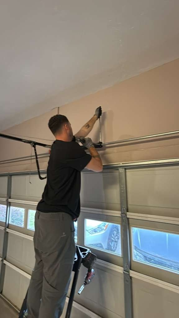 Technician on a ladder above a door with window panels