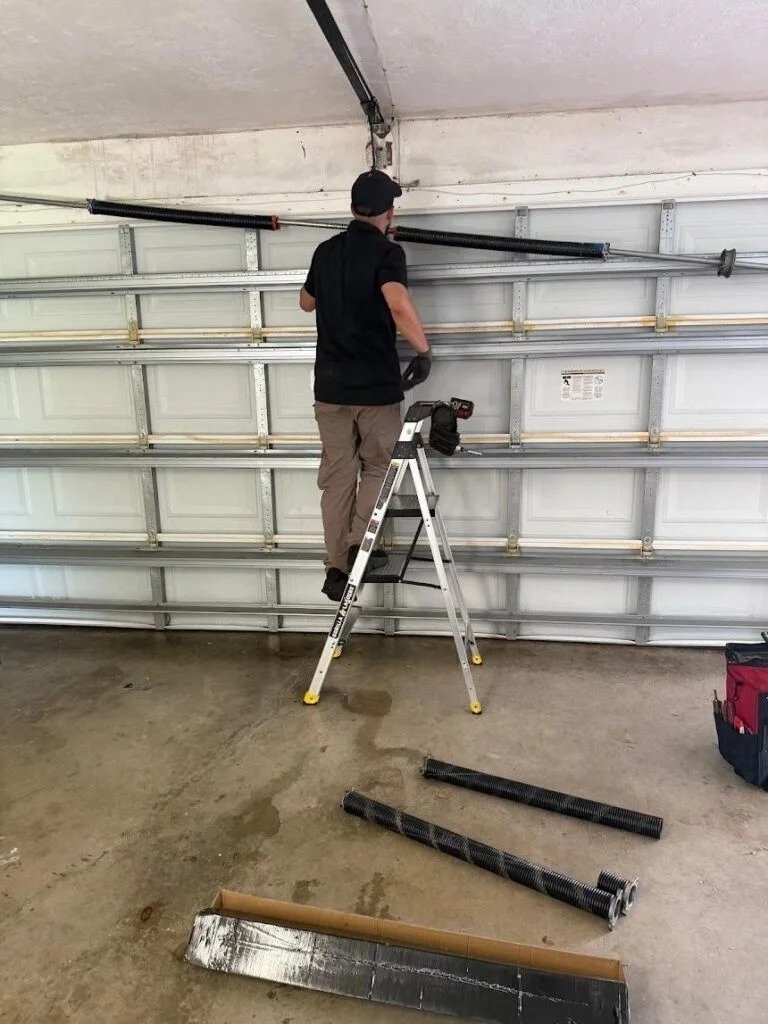 Technician on a stepladder at the torsion bar with track sections on the floor
