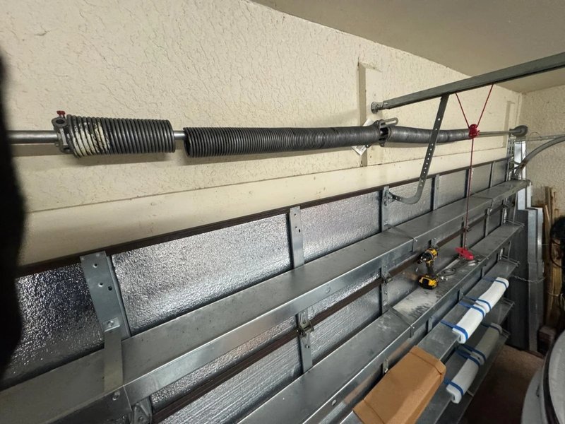 Extension spring running along the horizontal track of a garage door